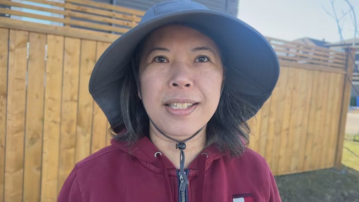 Une femme portant un chapeau fixe du regard l'objectif d'une caméra.
