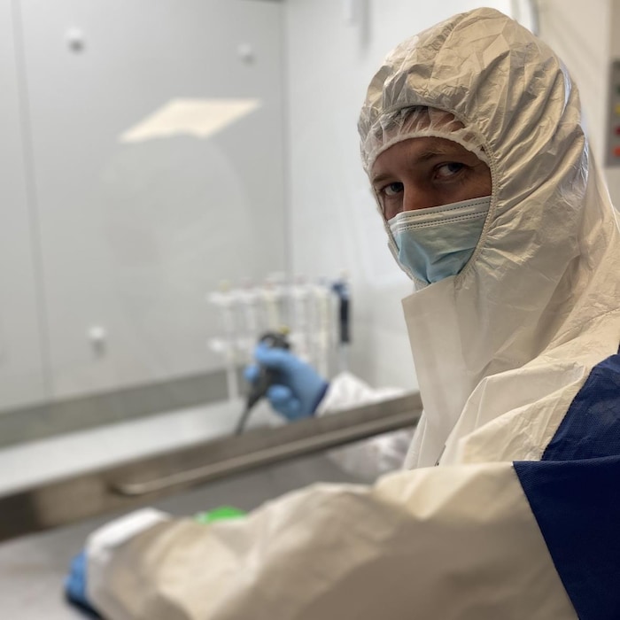 Un homme vêtu d'une combinaison de extortion  blanche fait des analyses dans un laboratoire, à Copenhague, au Danemark.
