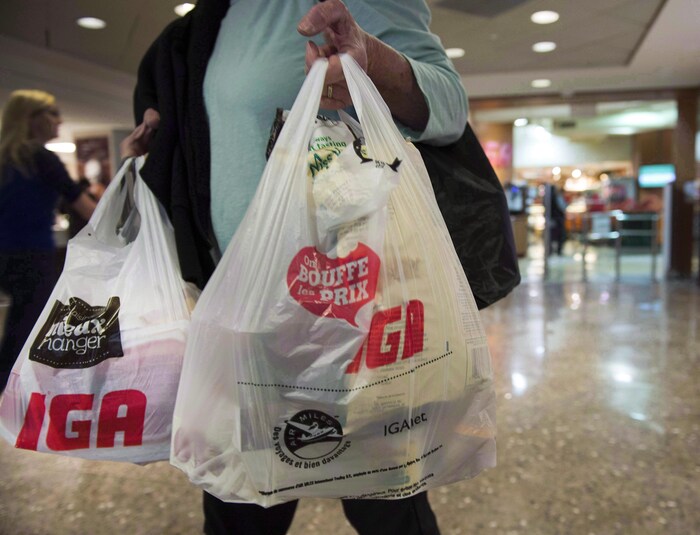 Une femme tient des sacs de plastique à la main.