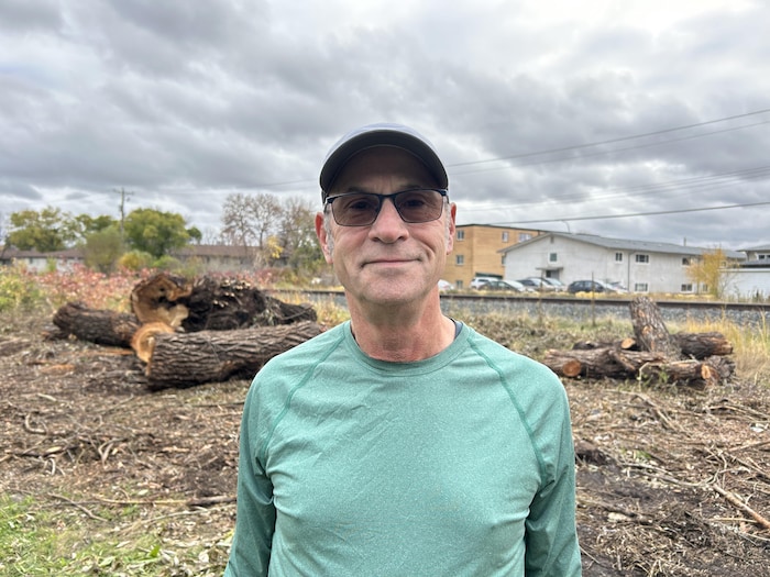 Un portrait de Scott Steen devant la voie ferrée et des restes d'arbres abattus.
