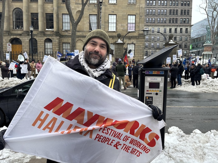Un homme brandit une grande bannière pendant une manifestation en hiver.