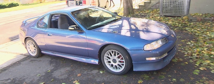 Un homme conduit une Honda 1992 bleue dans l'entrée de son stationnement.