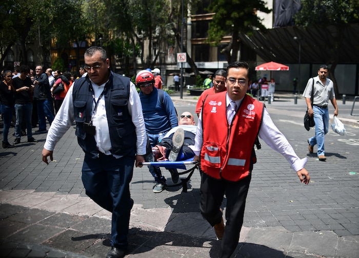 Un homme est transporté sur une civière après le tremblement de terre survenu mardi qui a secoué la capitale mexicaine.