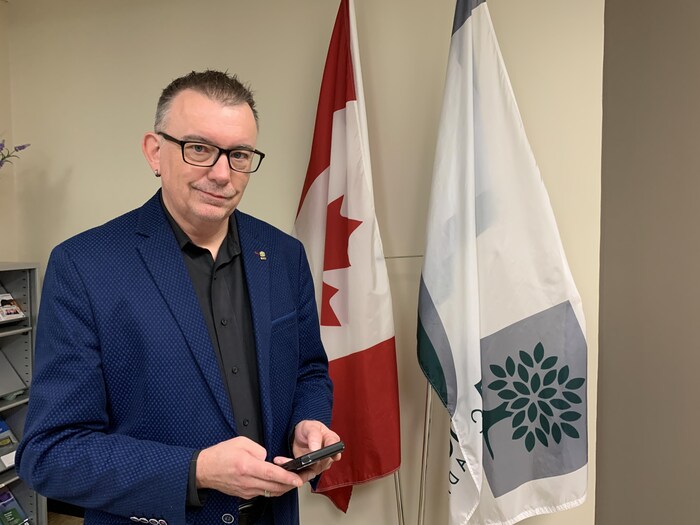 Shawn Lewis porte une chemise noire et une veste bleue