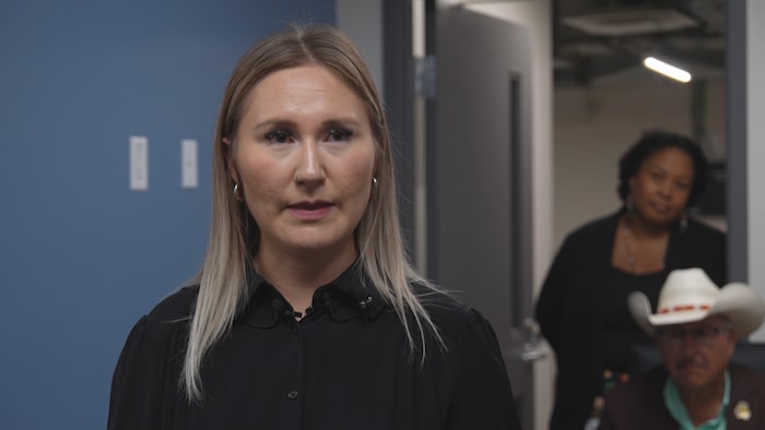 Une femme fixe du regard l'objectif d'une caméra.