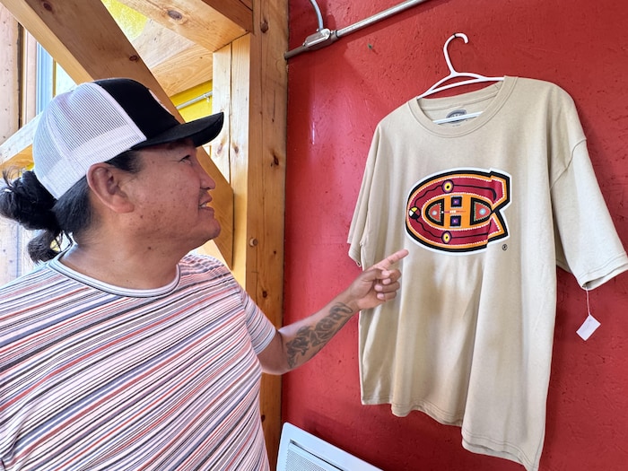 Une personne montre un chandail arborant une version autochtone du logo des Canadiens de Montréal.