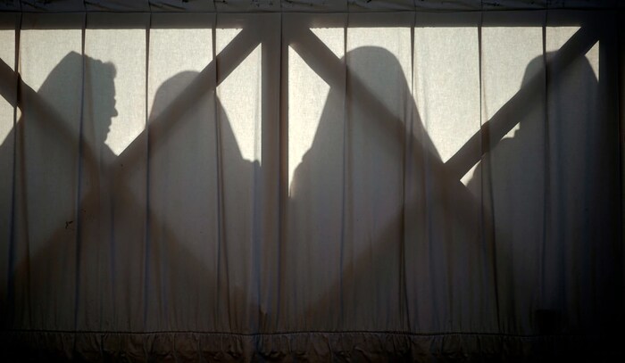 Les ombres de trois sœurs apparaissent sont projetées sur un mur. 