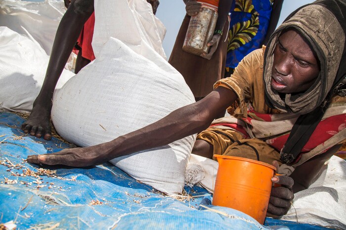 Une femme sud-soudanaise ramasse des graines qui traînent à la suite d'une distribution de nourriture