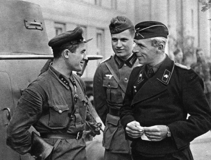 Trois hommes en uniforme militaire bavardent.