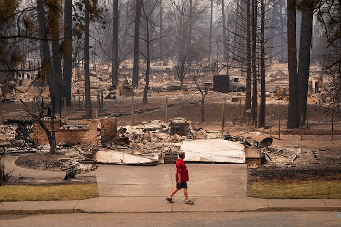 Un homme regarde les restes de maisons complètement détruites par les flammes.