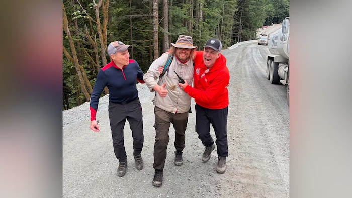 Trois hommes sourient sur un sentier.