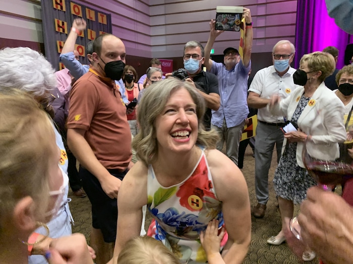 Entourée de partisans, Susan Holt sourit en se penchant vers son jeune enfant pour le prendre dans ses bras.