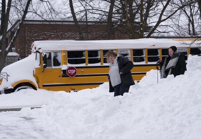 Des piétons passent près d'un autobus scolaire stationné à Mississauga.