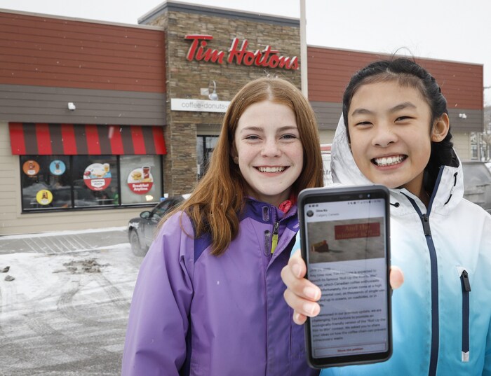 Aux côtés d'Eve Helman devant un Tim Hortons de Calgary, Mya Chau montre sur son cellulaire la pétition en ligne.