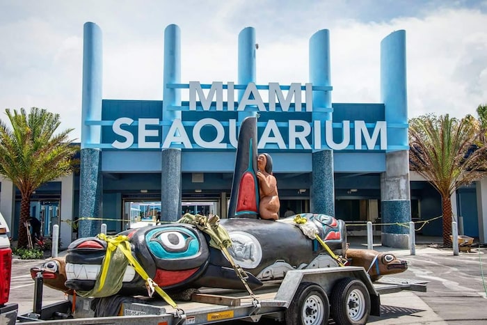Devant les bâtiments de l'Aquarium de Miami, un totem est couché sur une remorque.