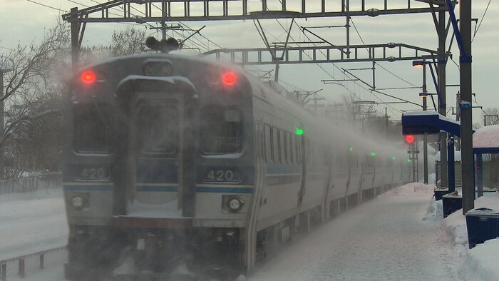 Un train voyage sous la neige dans la banlieue de Montréal.