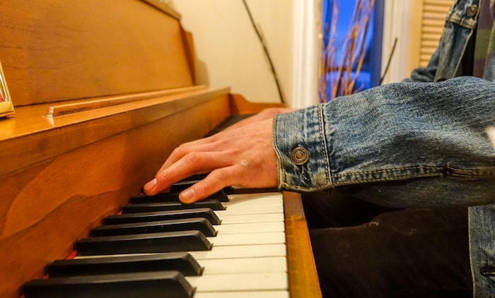 Un jeune homme photographié de manière anonyme joue du piano
