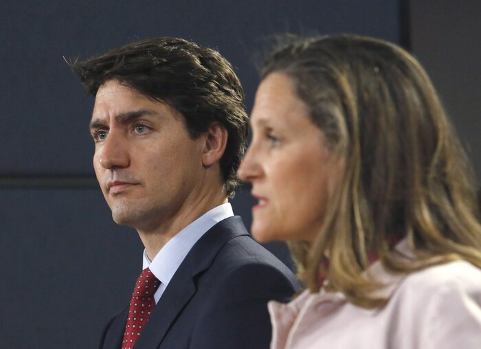 Justin Trudeau écoute Chrystia Freeland lors d'une conférence de presse