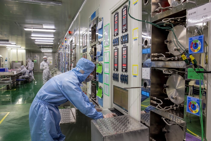 Un homme portant une combinaison de protection travaille dans une usine de fabrication de puces électroniques.