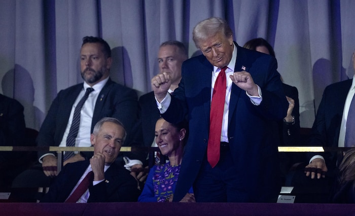 Donald Trump, debout, s'agite avec les deux poings fermés. Assis, Mark Carney parle à Claudia Sheinbaum.