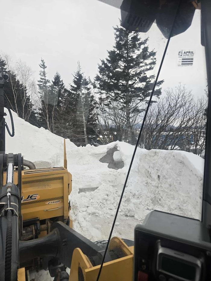 Un énorme trou dans un remblai de neige, pris en photo depuis une machinerie lourde servant à déneiger.