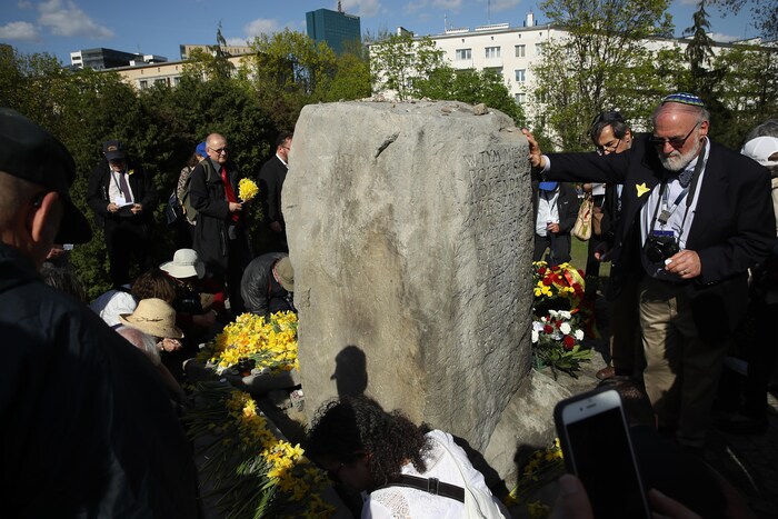 Jonquilles épinglées aux vêtements, des gens ont déposé des fleurs sur un monument érigé sur un monticule, à Varsovie, qui est à la fois une fosse commune et l'endroit où se trouvait le bunker de commandement des partisans juifs qui ont combattu dans le ghetto de Varsovie. 