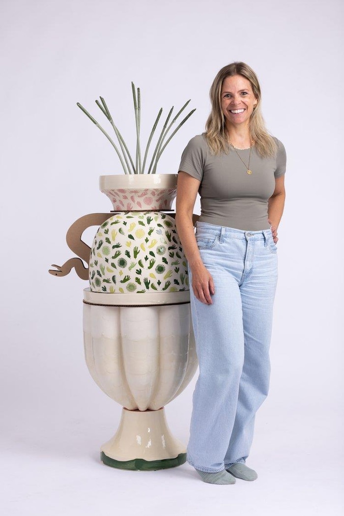 Une femme à côté d'un immense cookware de fleurs.