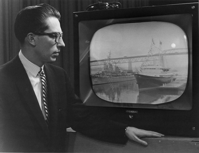 Dans un studio de télévision, l'annonceur Bruce Marsh fait la description de l'inauguration de la Voie maritime du Saint-Laurent, debout devant un moniteur de télévision dans lequel on voit le yacht royal Britannia faire son entrée dans la Voie
maritime.