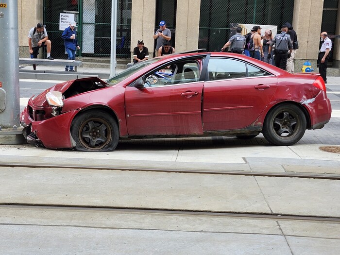 Une voiture endommagée après avoir percuté un obstacle sur la voie du train léger de la ligne Valley, au centre-ville d'Edmonton, le 19 juillet 2024.