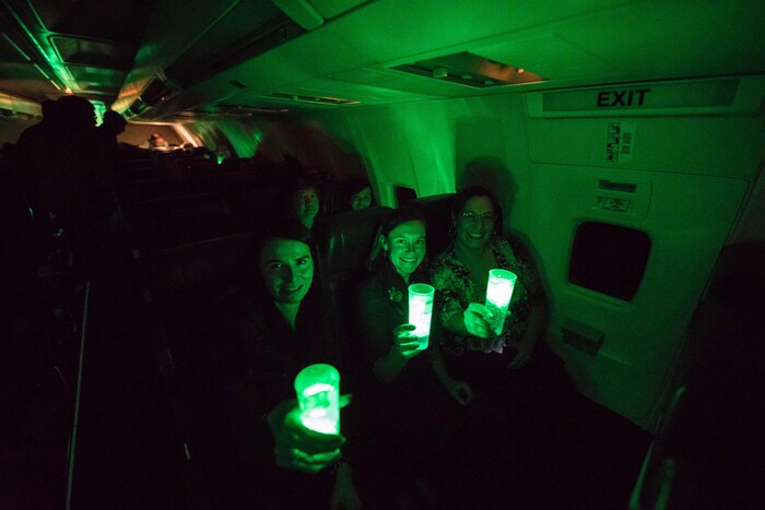 Des passagers de l'avion tiennent des verres illuminées, de couleur verte