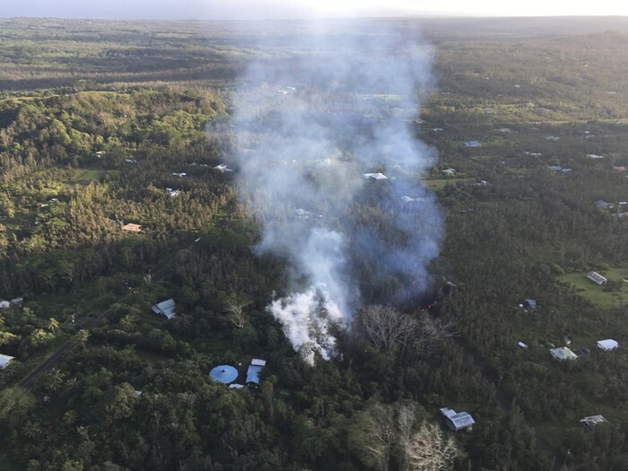 Photo aérienne montrant un panache de fumée blanche dans un secteur résidentiel boisé. Plusieurs résidences sont visibles.