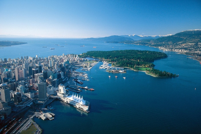 Vue aérienne du Parc Stanley et du centre-ville ouest de Vancouver. On voit des bateaux et les montagnes à l'horizon.