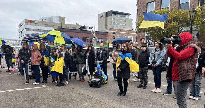 Plusieurs dizaines de personnes parmi une foule, avec des drapeaux de l'Ukraine et des parapluies bleu et jaune.