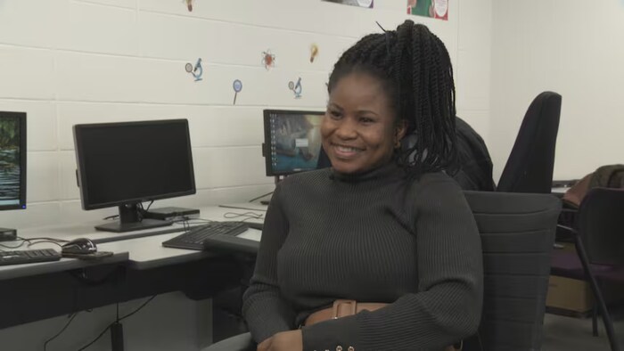 Une femme est assise dans un bureau, esquissant un sourire.