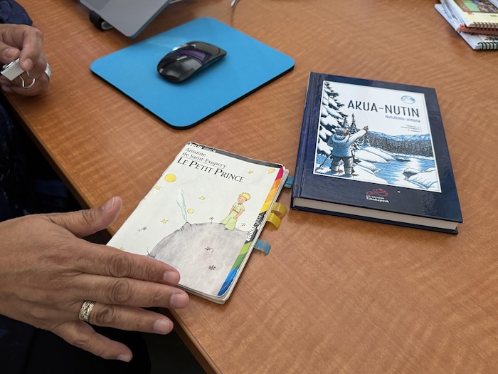 Deux livres sont posés sur une table où on aperçoit une main.