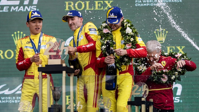 L'équipe gagnante des 24 Heures du Mans célèbre sur le podium avec du champagne et le trophée.