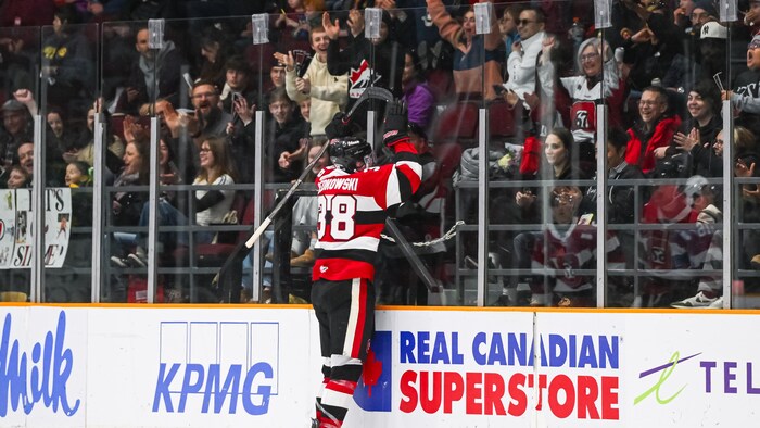 Un joueur de hockey junior célèbre un but avec la foule.