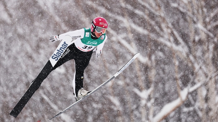 Une skieuse s'élance dans les airs, sous la neige.