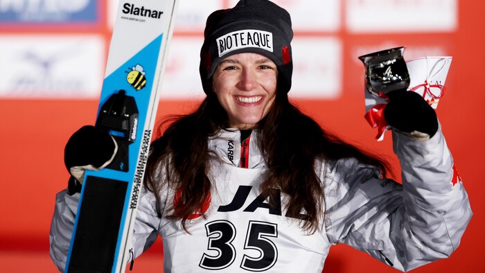 Elle pose pour la photo avec skis et trophée à la main.