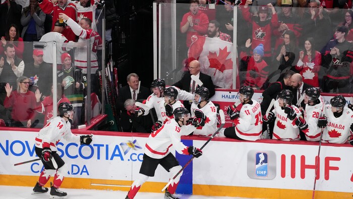 Un joueur de hockey célèbre au banc avec ses coéquipiers.