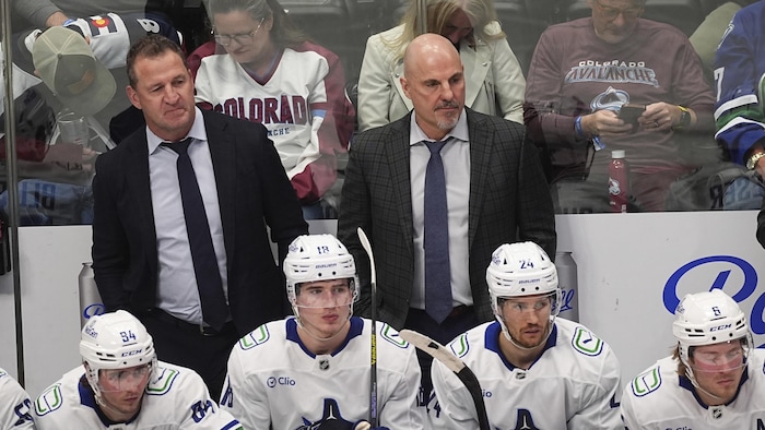 Deux hommes derrière le banc d'une équipe de hockey.