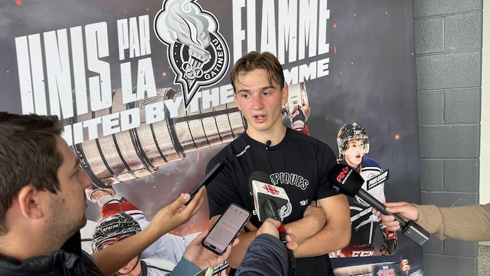 Un joueur de hockey s'adresse à des journalistes après un entraînement.