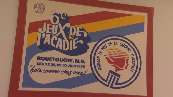Affiche avec inscription 6e Jeux de l'Acadie, Bouctouche. Slogan: Fais comme chez vous! et Jeunesse, le Pays de la Sagouine t'accueille.
