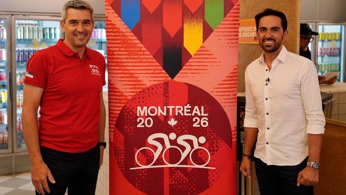 Deux hommes se tiennent devant une affiche de Montréal 2026