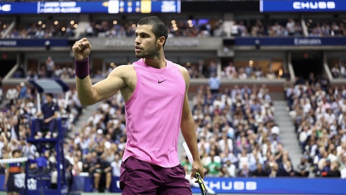 Un joueur de tennis sur le court central, devant la foule, serre le poing.