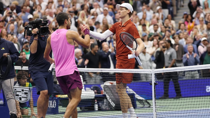 Deux joueurs de tennis se serrent la main au filet.