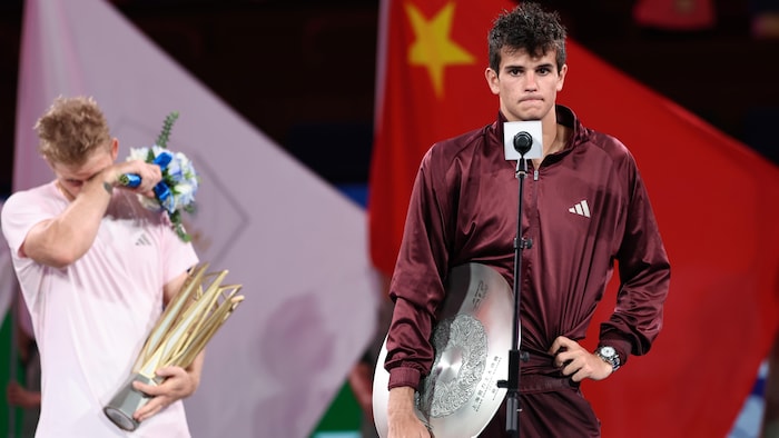 Il tient son trophée de finaliste, l'air déçu.