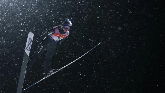 Alexandria Loutitt en plein vol plané la nuit au-dessus de la piste de Lake Placid.