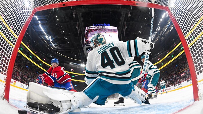 Un hockeyeur glisse la rondelle du revers dans le filet à la gauche du gardien.