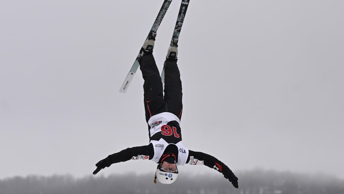 Elle est en plein saut dans les airs, tête vers le bas.